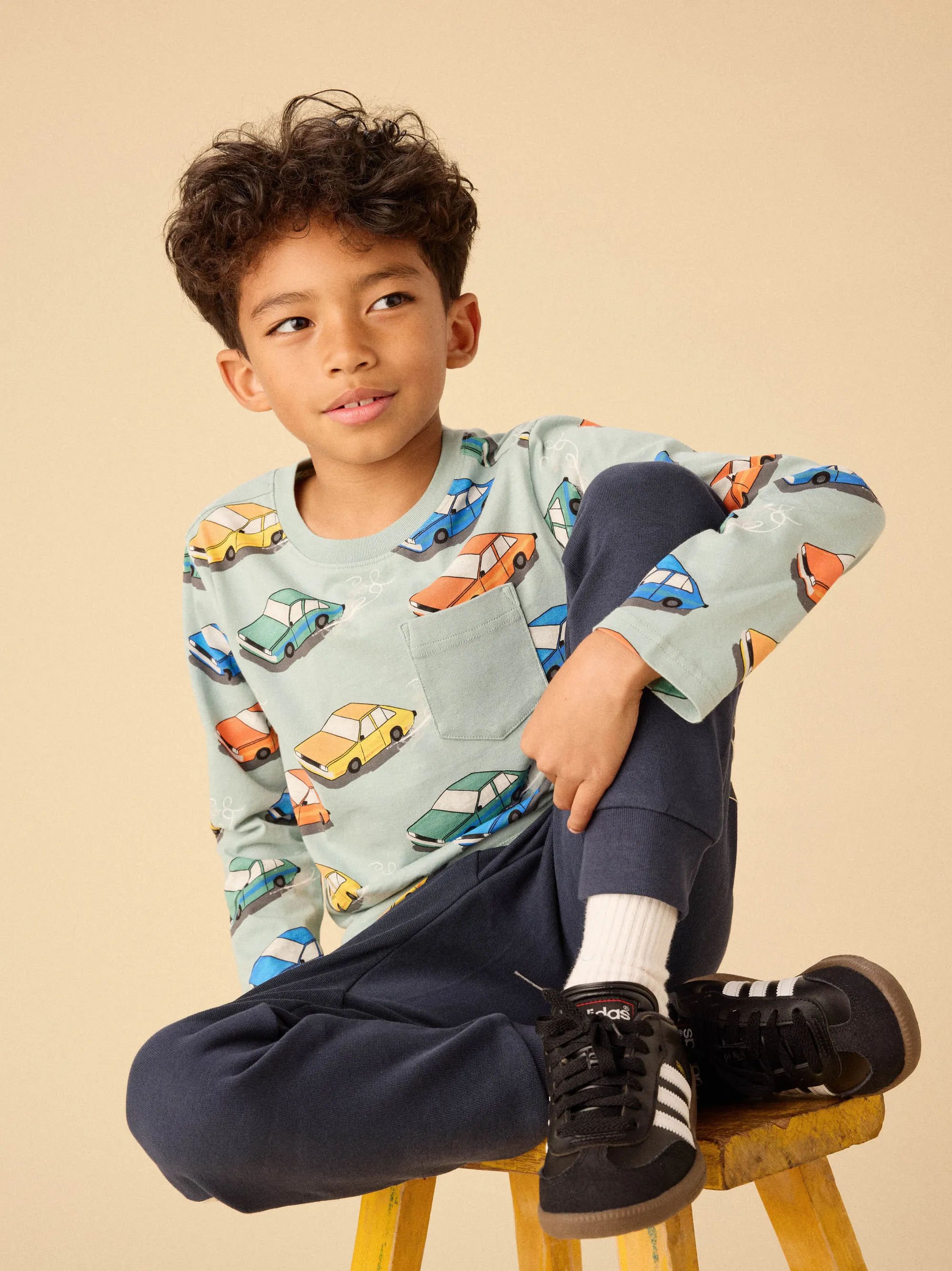 Two kids wearing playful animal-themed sweaters hanging from a branch. Cheerful children's clothing with fun designs.
