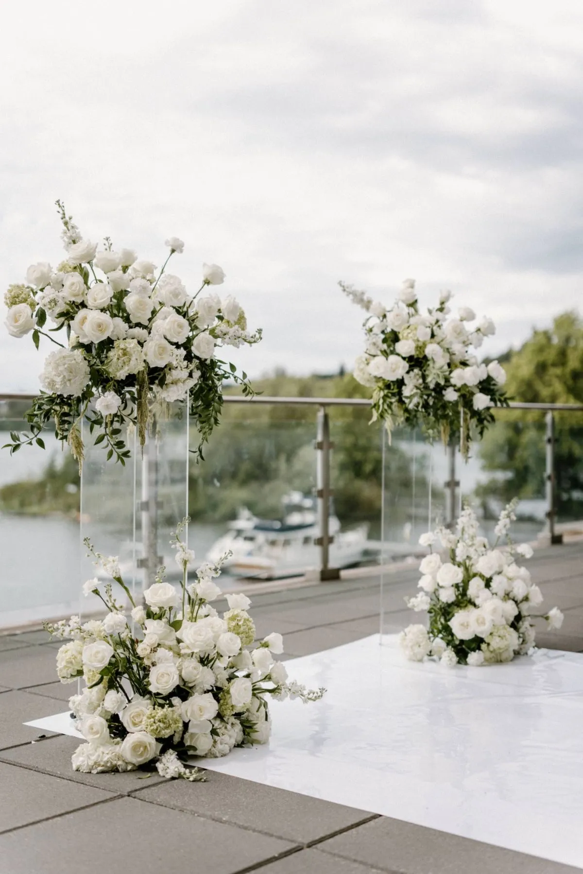 Elegant outdoor ceremony setup with chairs, floral archway, and aisle decorations. No human shapes.