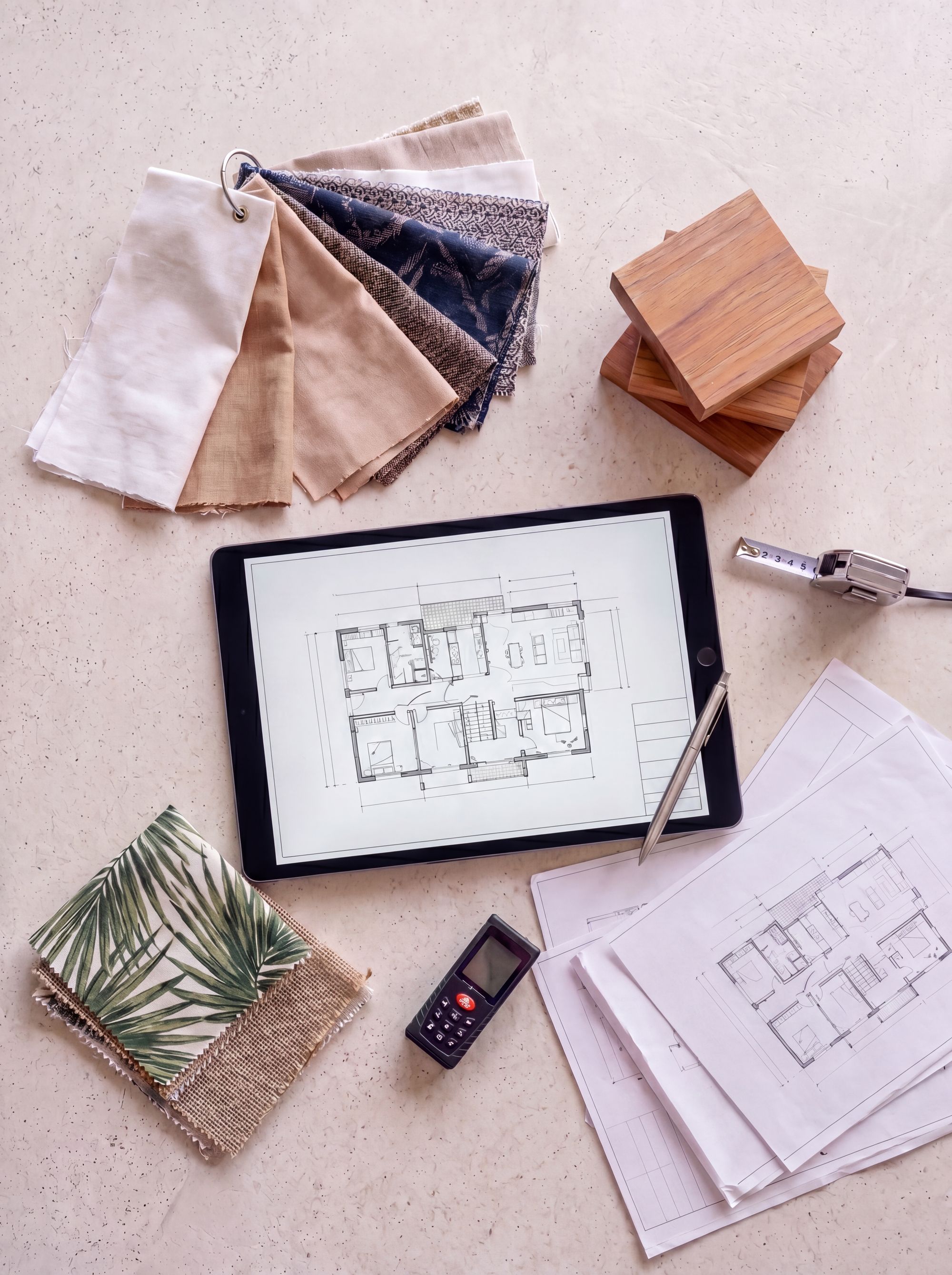 Flat-lay mood board with fabric swatches, wood samples, sketch notebook, and floor plans