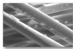 Manufacturer micrograph showing copper fragments on the yarn surface