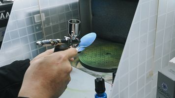 Spraying paint on a plastic spoon.