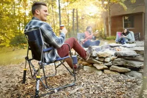Man sitting in a a chair next to an outdoor fire.