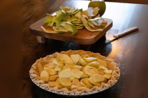 Sliced applies in pie crust on wooden surface.