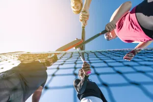 Four people holding pickleball paddles or a net
