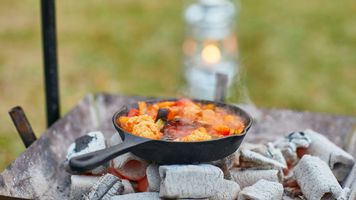 Cast iron skillet on outdoor fire.