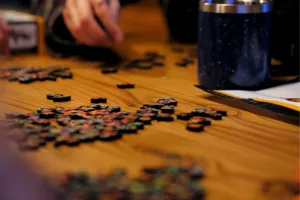 Person assembling a puzzle on a wood table.