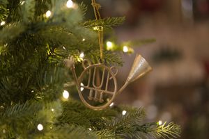 Gold horn Christmas ornament hanging on a lighted tree.