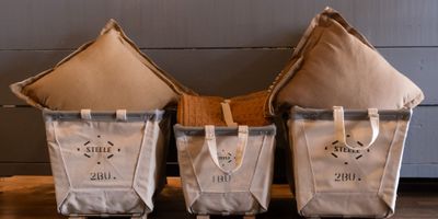 Three Steele canvas bins in front of grey ship-lap wall