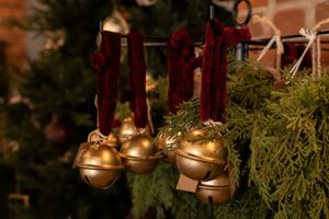 Brass bells hanging from greenery by velvet ribbon.