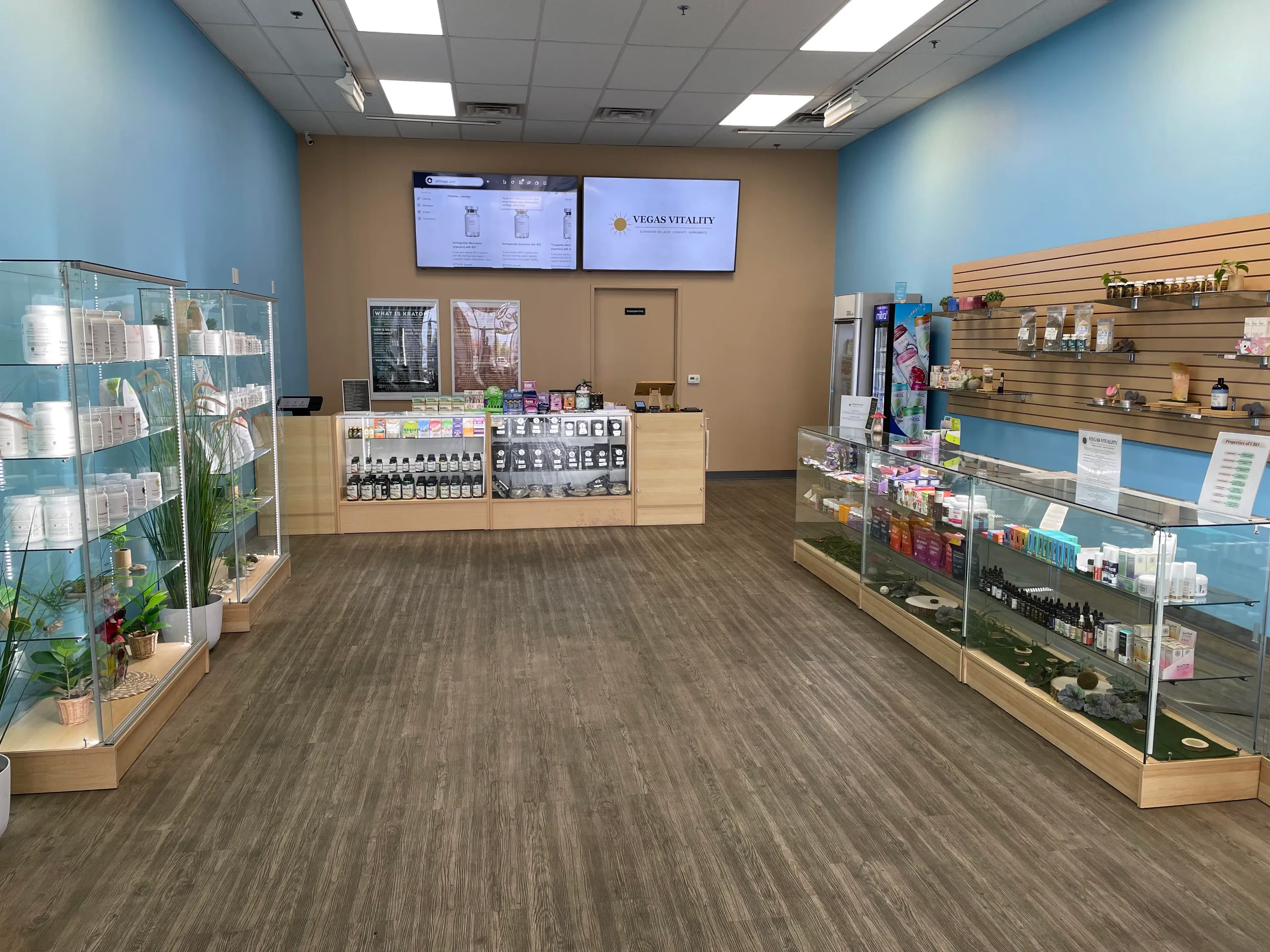 Inside Vegas Vitality: glass display cases of supplements, kratom and kava, with the checkout counter and menu screens at the back