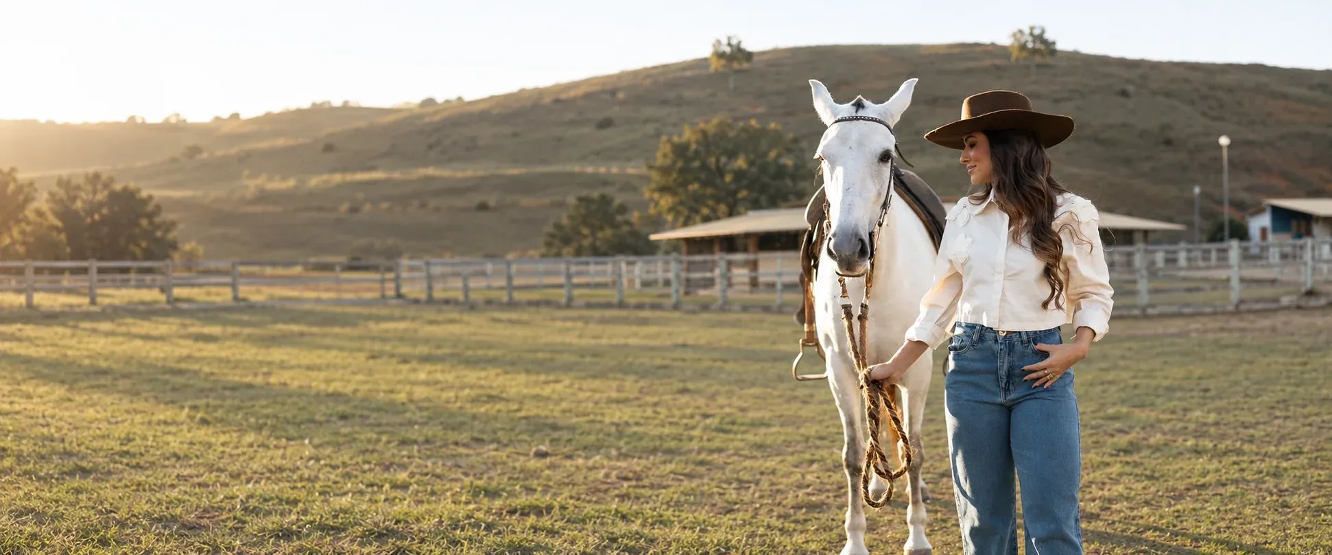 Mulher com calças wide leg Nexum ao lado de um cavalo branco numa quinta brasileira