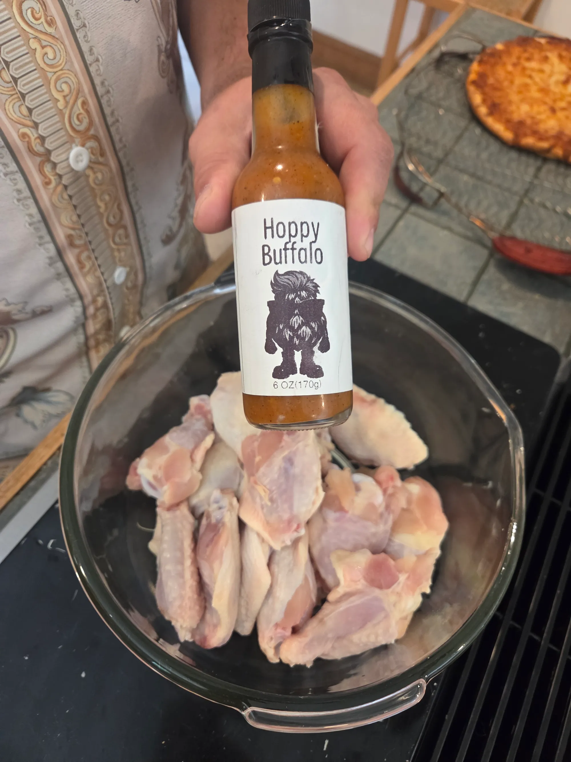 Raw chicken wings being tossed in a large mixing bowl with bright red Hoppy Buffalo Sauce, showing the coating process, no human shapes