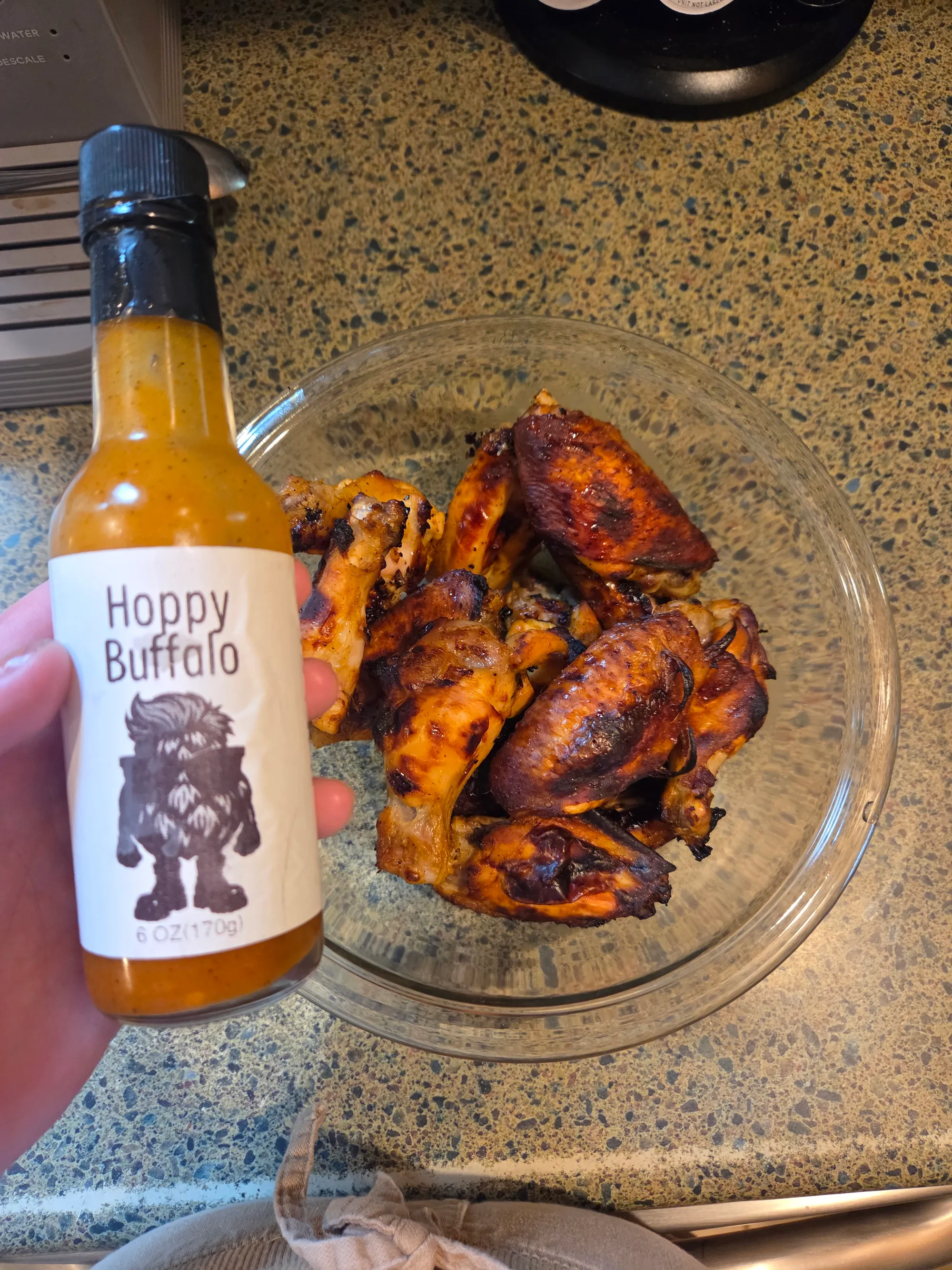 Video thumbnail showing wings being tossed in additional Hoppy Buffalo Sauce in a large bowl, with sauce dripping and coating each wing evenly, no human shapes