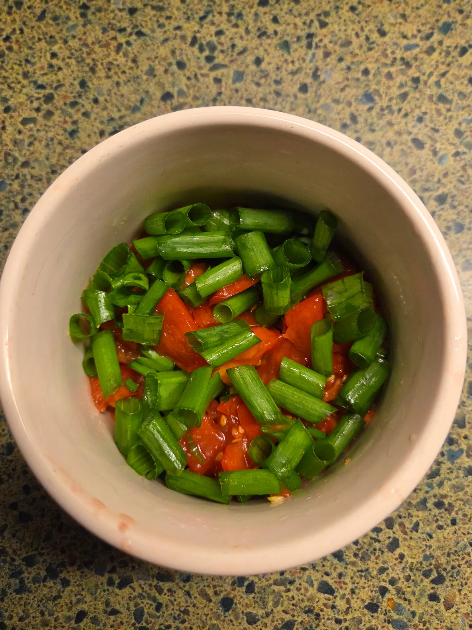 Freshly diced tomato and jalapeño in a small bowl, creating a vibrant salsa mixture with bright red tomatoes and green jalapeño pieces. Do not generate human shapes.