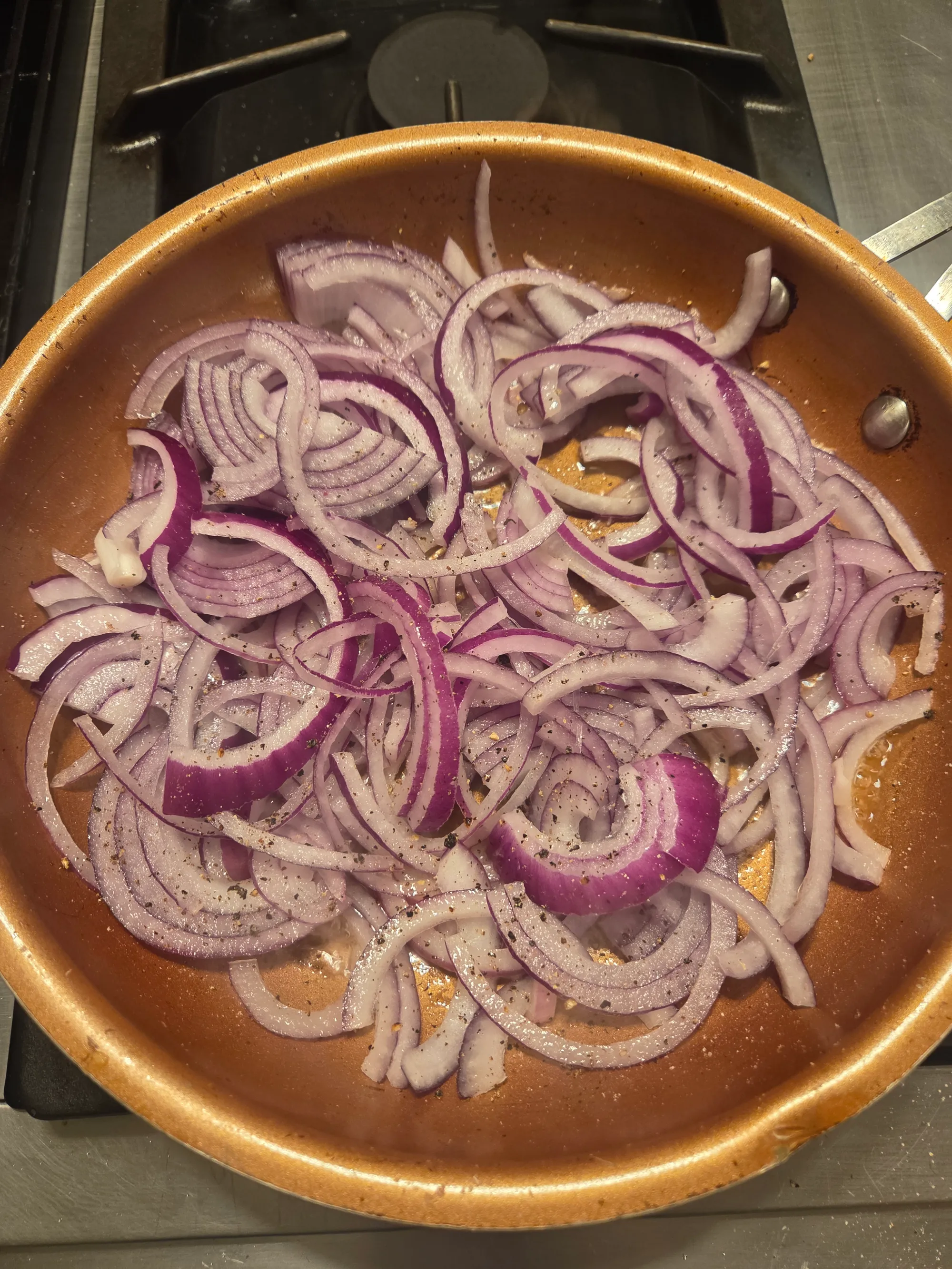 Sliced onions cooking in a skillet until golden brown and caramelized. No human shapes.