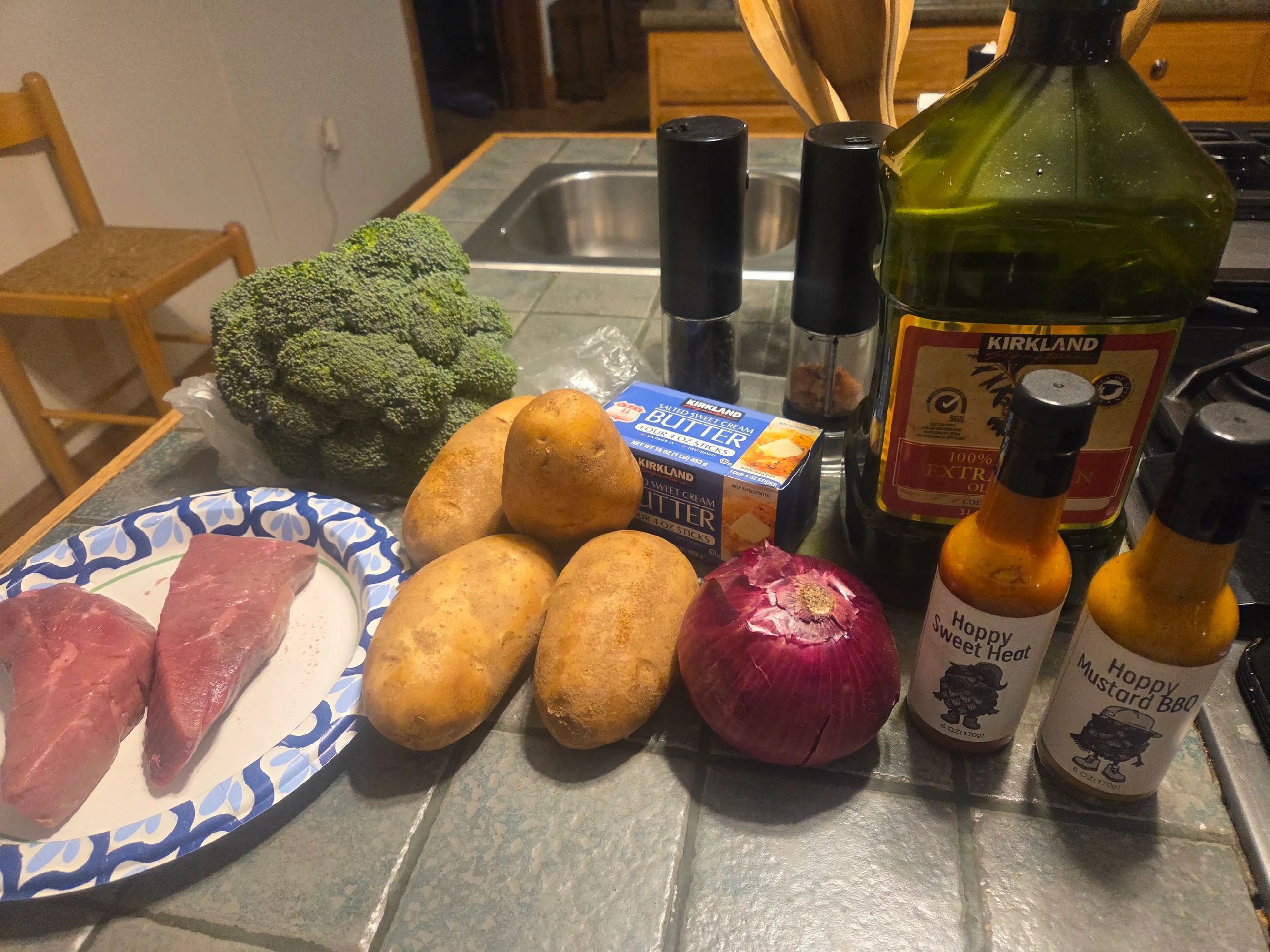 Plated meal featuring sirloin steak glazed with Hoppy Mustard BBQ sauce, broccoli tossed with Hoppy Sweet Heat, and caramelized onion mashed potatoes. No human shapes.